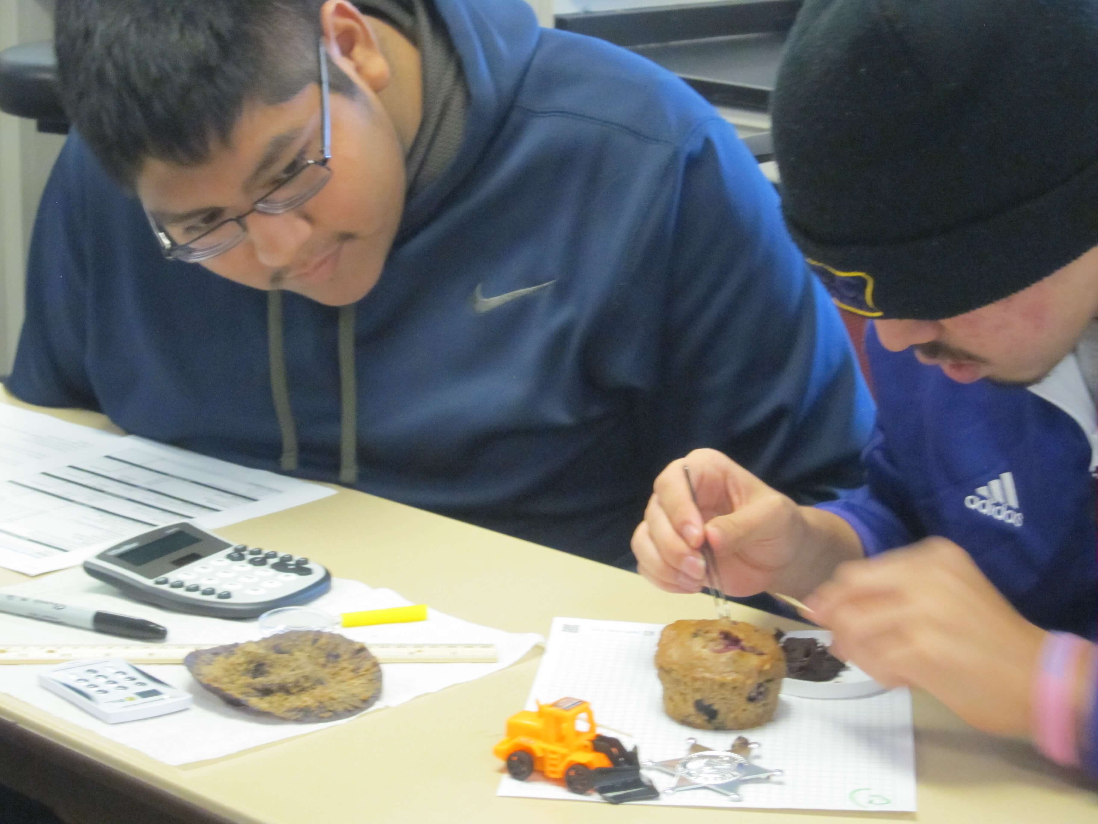 Two individuals participate in muffin mining exercise to learn about copper mining.
